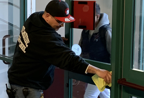 Riverside High School custodian wiping down the door handle to the principal's office.